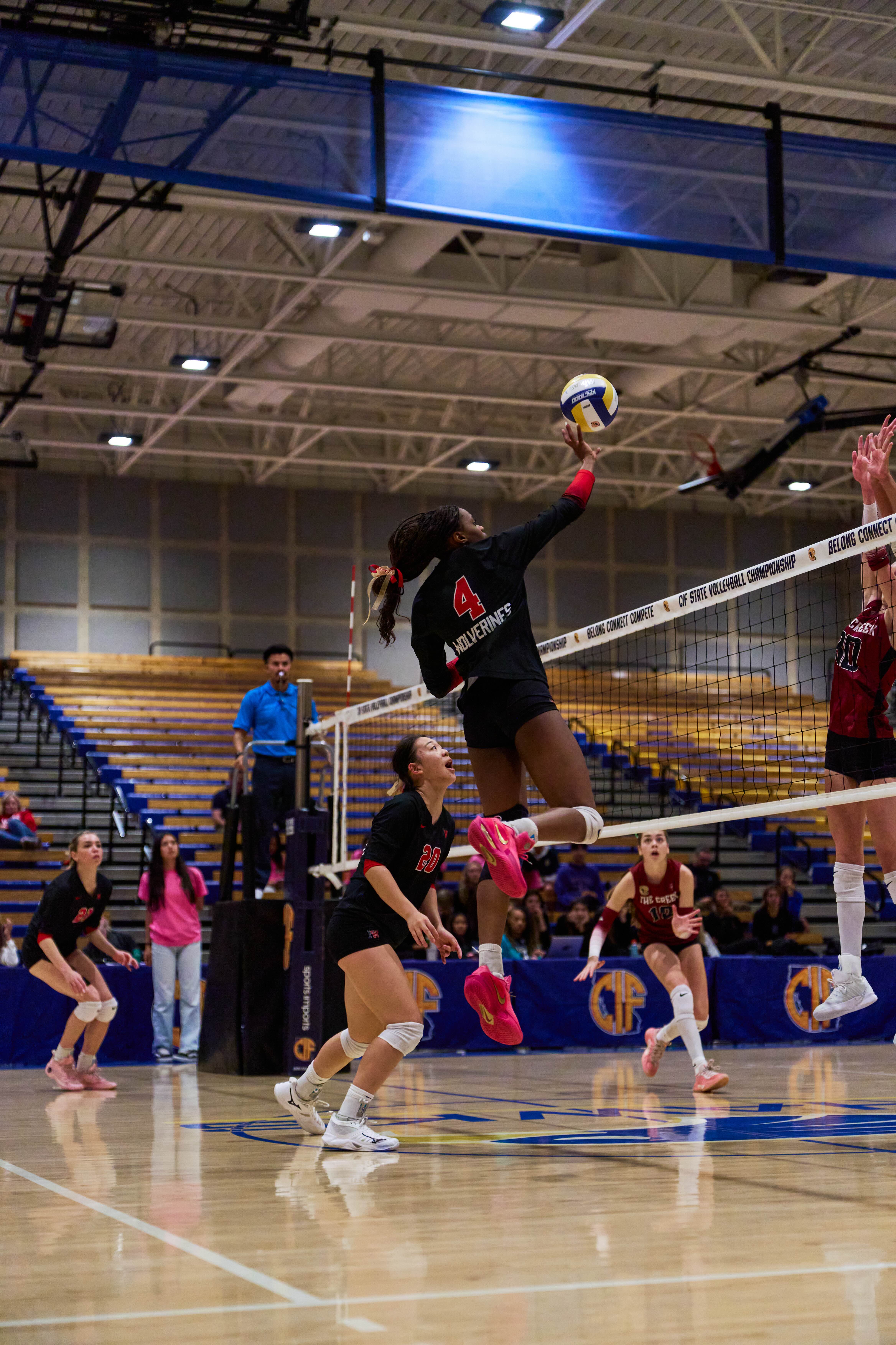 Lauryn Lewis airborne above the net, reaching to attack the ball at the CIF State championship.