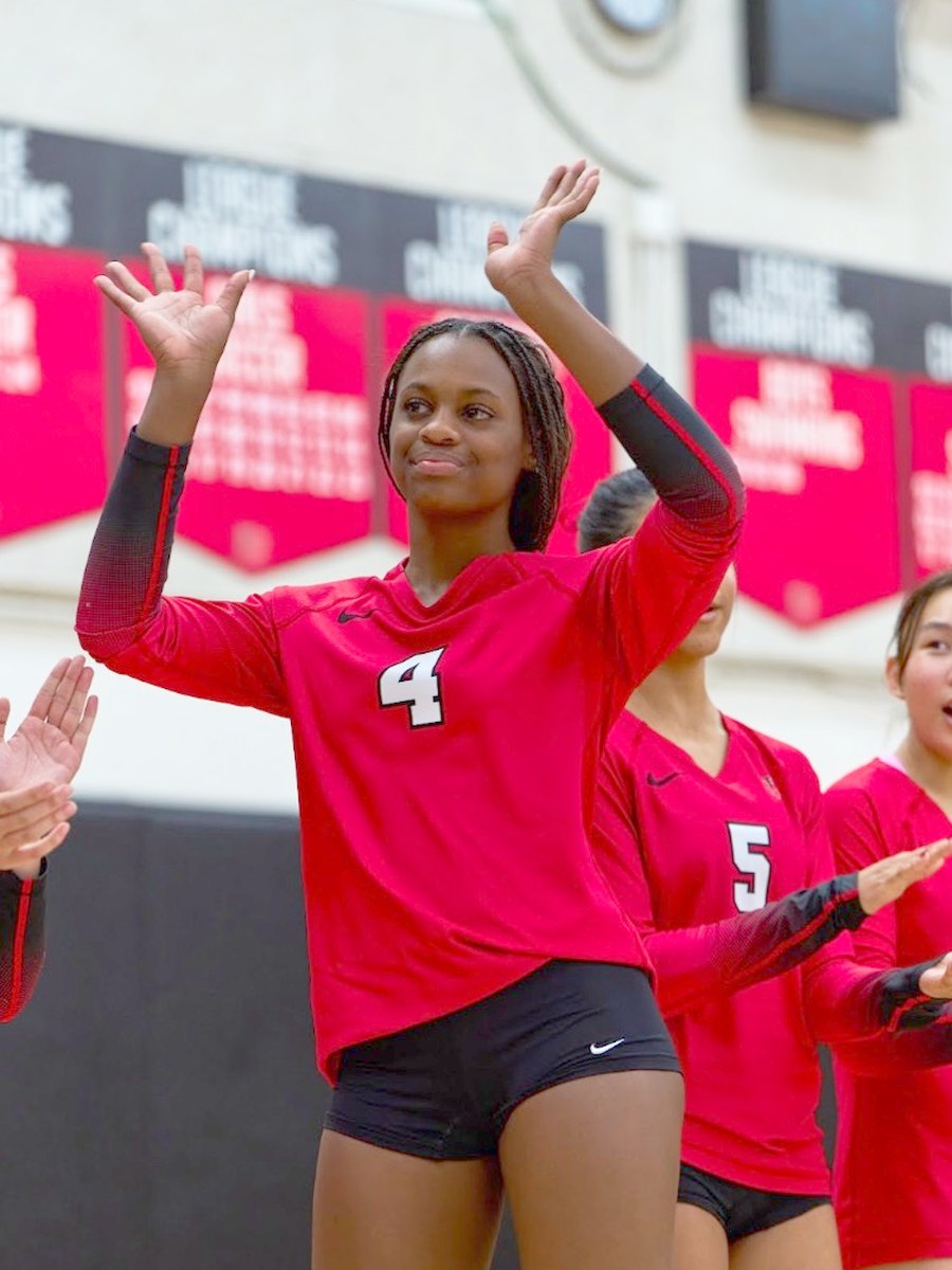 Lauryn Lewis applauding with her team beneath the Harvard-Westlake league champion banners.
