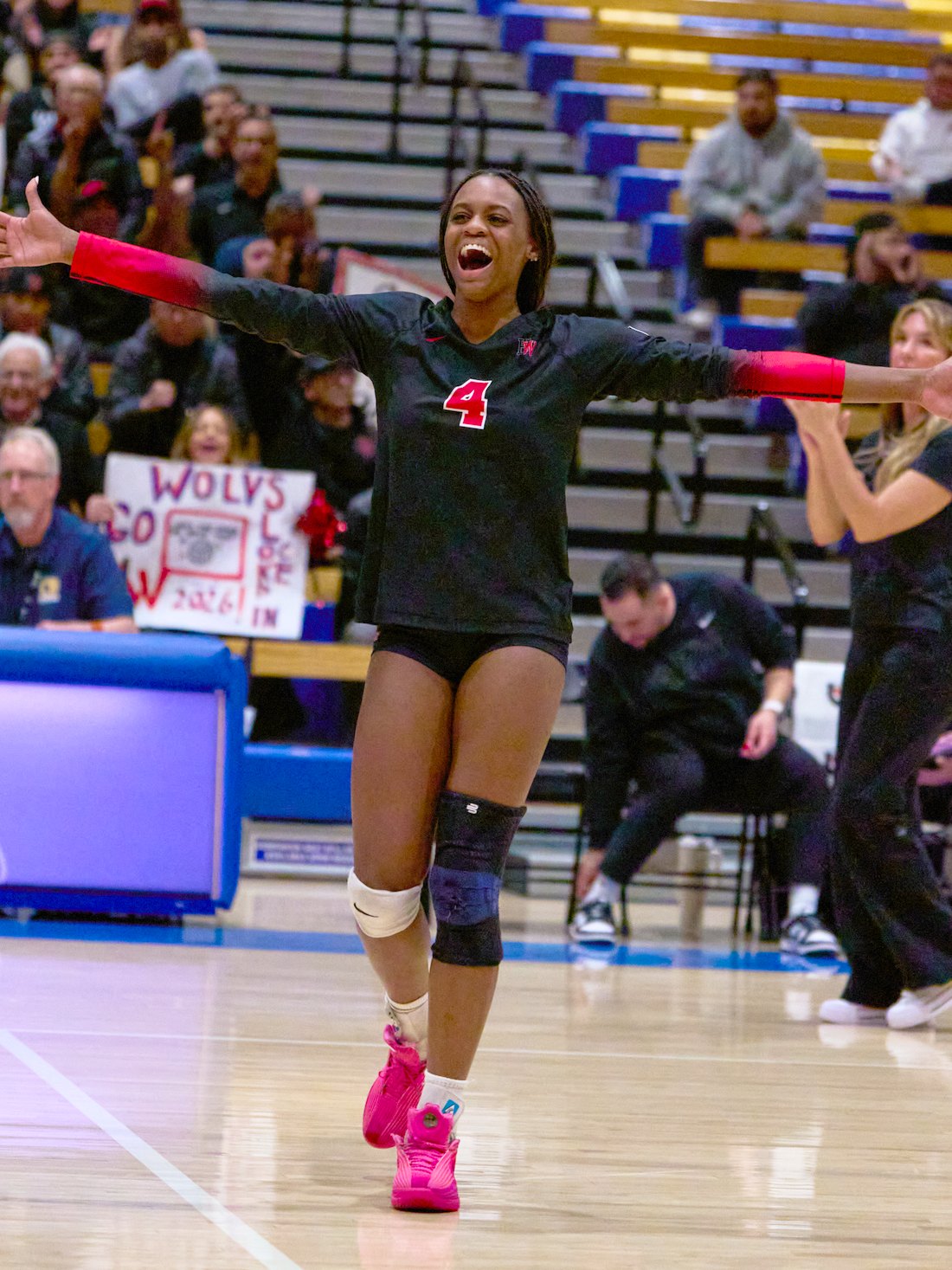 Lauryn Lewis running down the court with both arms outstretched after a point.