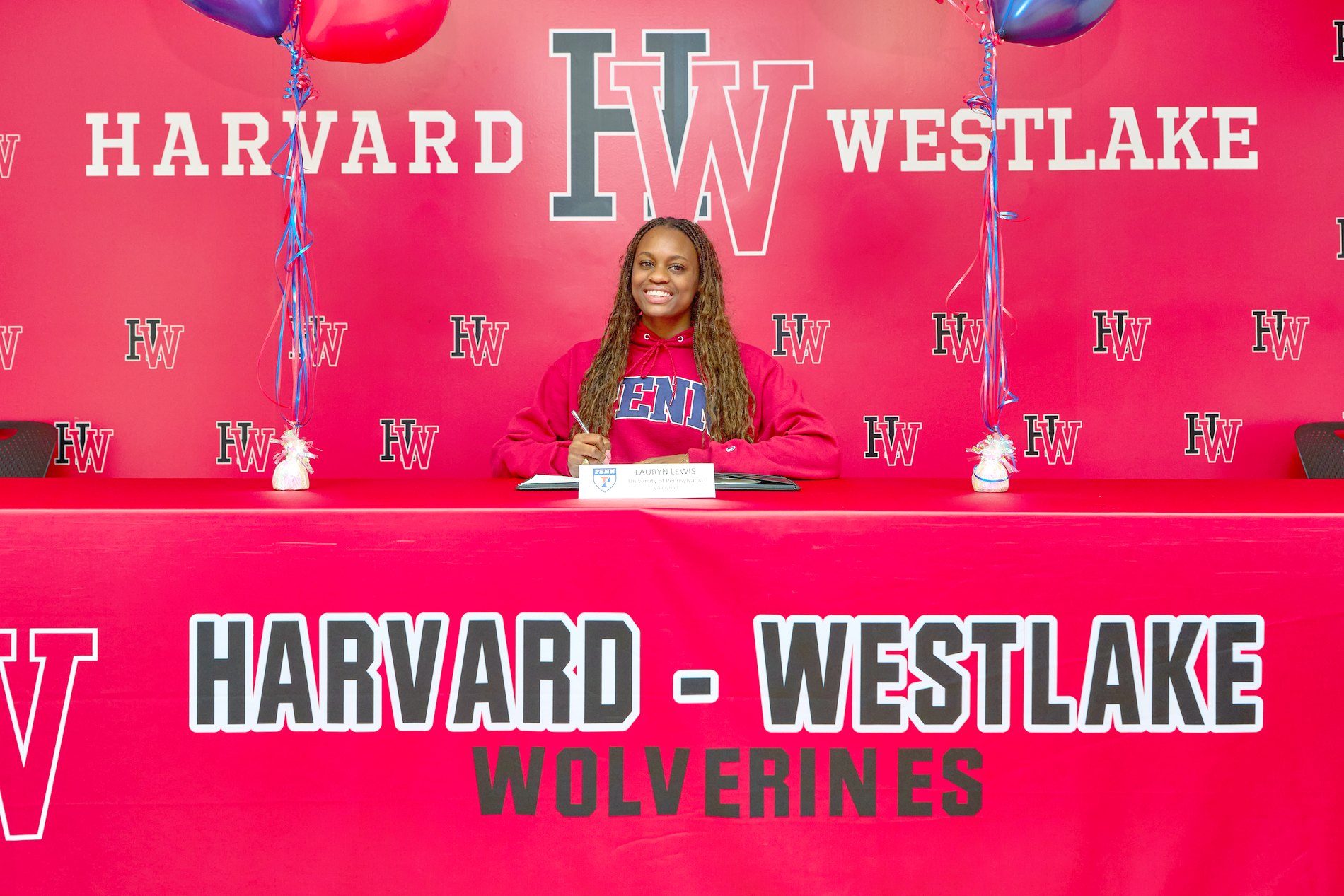 Lauryn Lewis at her signing day table in a Penn hoodie in front of a Harvard-Westlake backdrop.