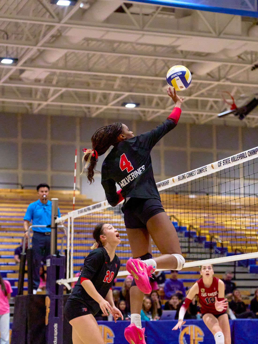 Lauryn Lewis at the top of her jump, attacking the ball at the net during the state championship.